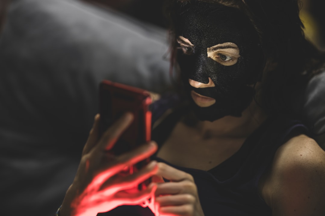 woman in black mask holding red smartphone - Photo by engin akyurt on Unsplash